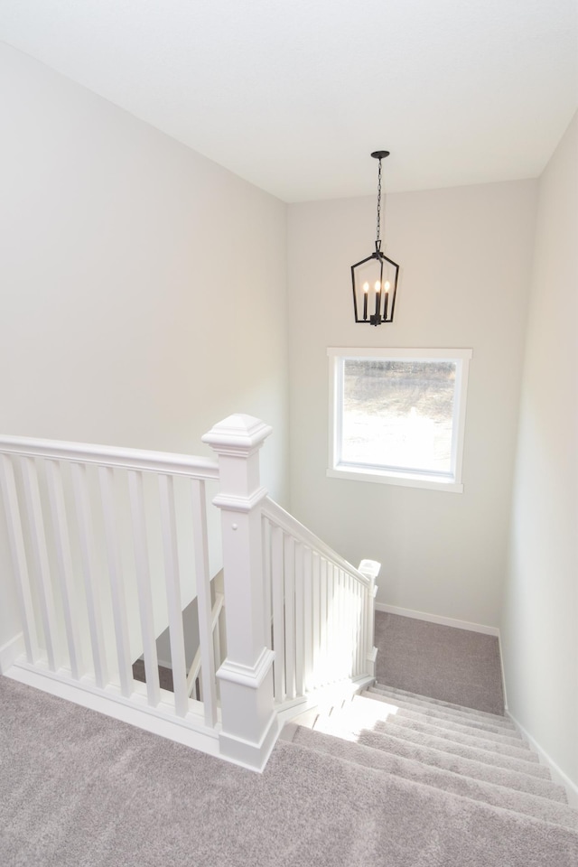 staircase featuring carpet floors and an inviting chandelier