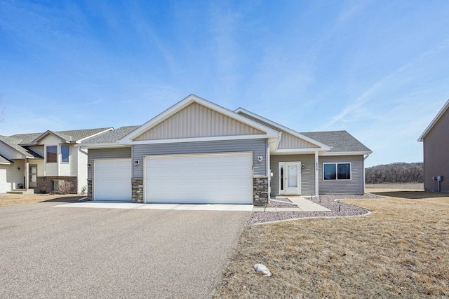 view of front of house featuring aphalt driveway, stone siding, board and batten siding, and a garage