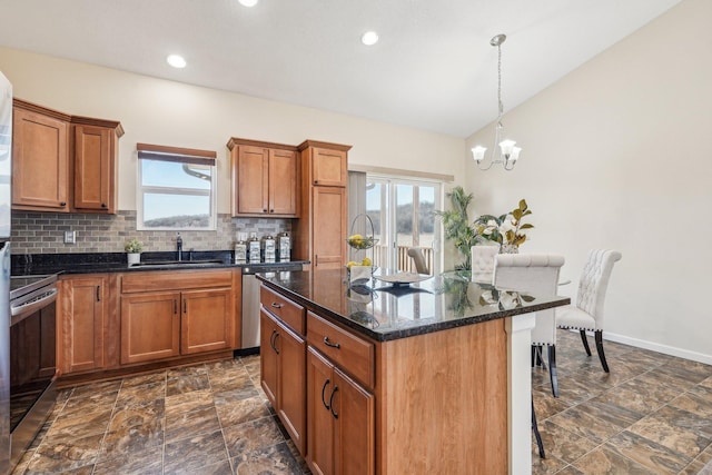 kitchen with backsplash, a breakfast bar area, brown cabinetry, stainless steel appliances, and a sink