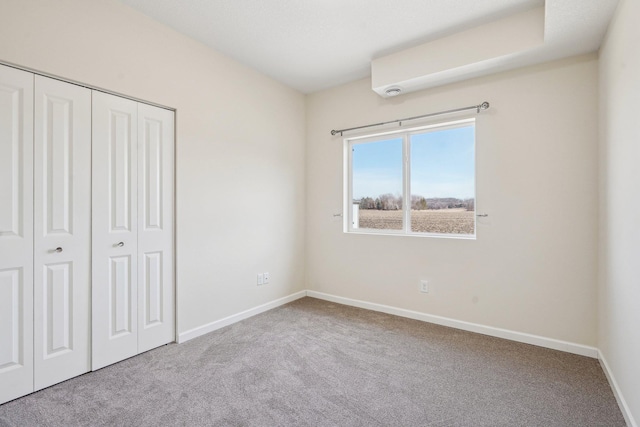 unfurnished bedroom with carpet, a closet, and baseboards