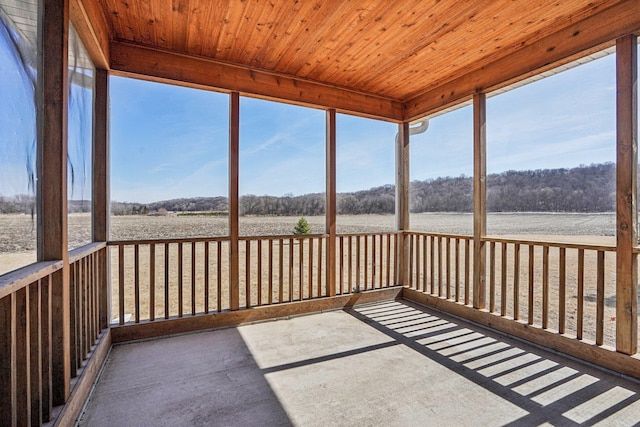 unfurnished sunroom with wooden ceiling, plenty of natural light, and a rural view