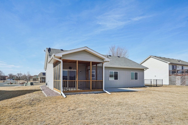 back of property with a yard, roof with shingles, and a sunroom