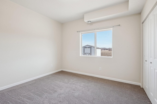 unfurnished bedroom with a closet, carpet floors, and baseboards