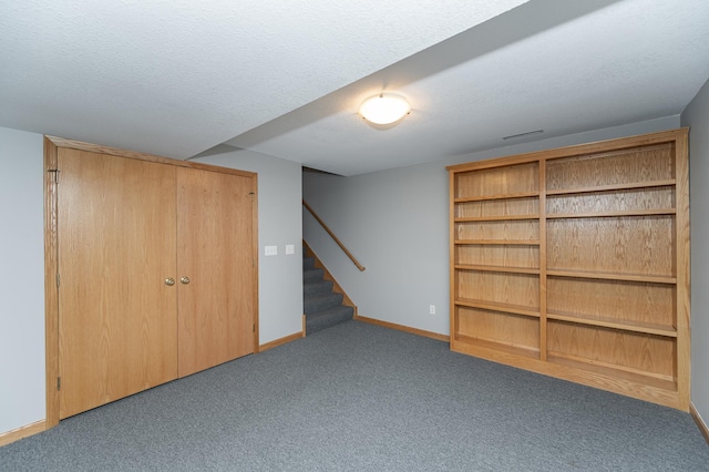 finished below grade area with stairway, carpet floors, a textured ceiling, and baseboards