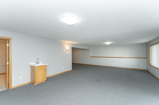 interior space with wet bar, baseboards, carpet floors, and a sink