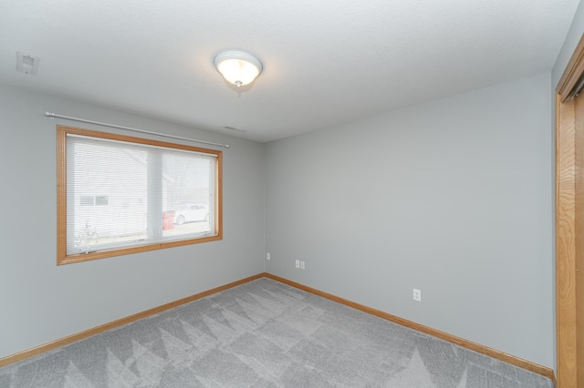 spare room featuring visible vents, baseboards, and light colored carpet