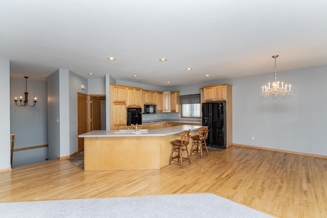 kitchen featuring a chandelier, a spacious island, black appliances, and a sink