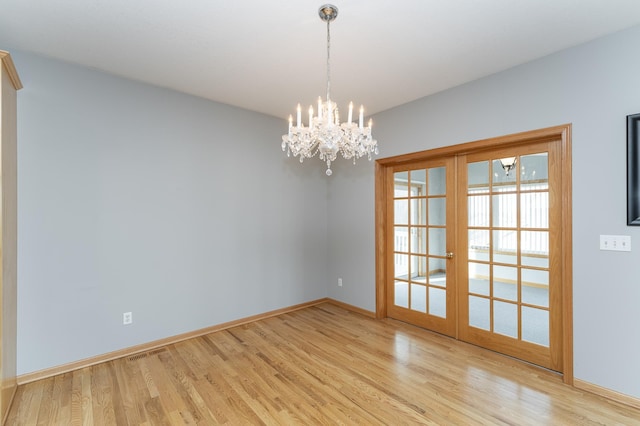 unfurnished room with visible vents, baseboards, french doors, an inviting chandelier, and light wood-style floors