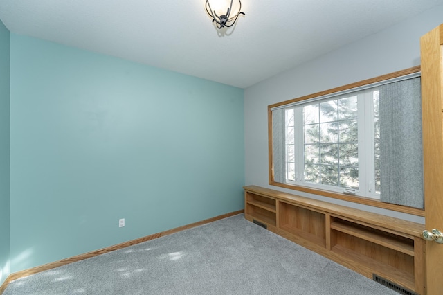 spare room featuring carpet flooring, baseboards, and visible vents