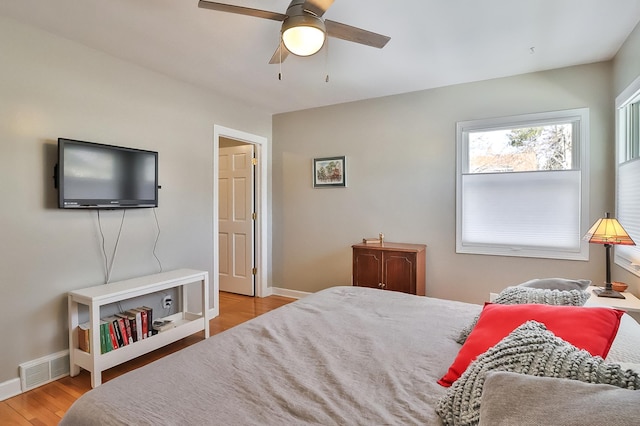 bedroom featuring light wood finished floors, visible vents, ceiling fan, and baseboards