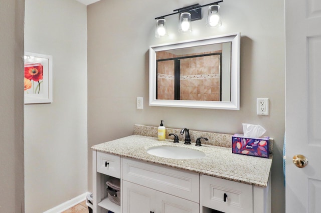 bathroom with baseboards, tiled shower, and vanity