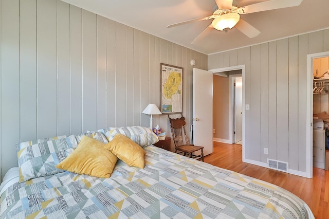 bedroom featuring a walk in closet, wood finished floors, visible vents, and ceiling fan