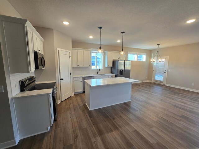 kitchen featuring a kitchen island, dark wood finished floors, white cabinets, appliances with stainless steel finishes, and tasteful backsplash