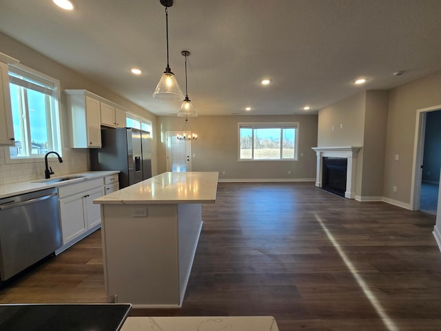 kitchen with a kitchen island, a fireplace, a sink, appliances with stainless steel finishes, and open floor plan