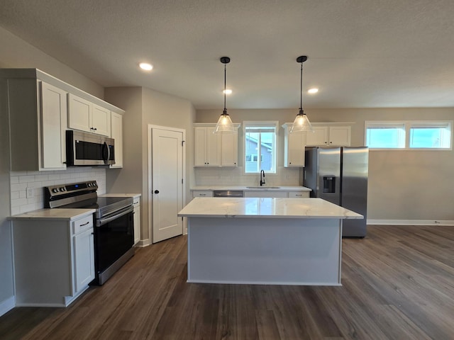 kitchen featuring dark wood-style floors, baseboards, a kitchen island, stainless steel appliances, and white cabinets