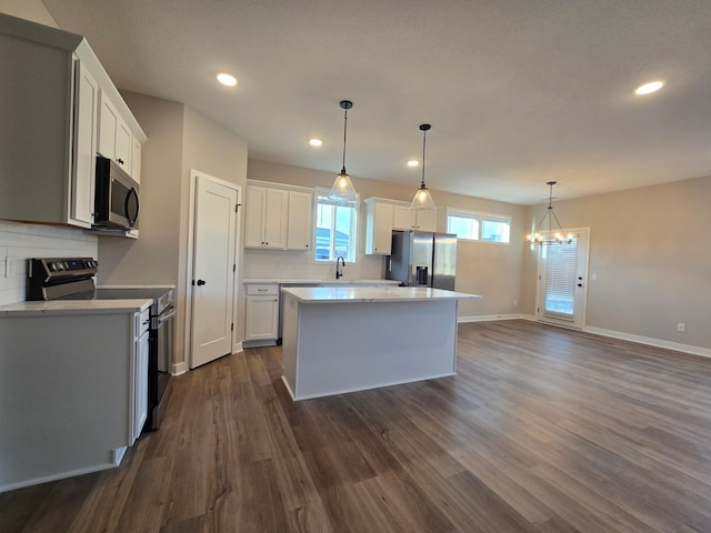 kitchen with stainless steel appliances, backsplash, dark wood-style floors, and light countertops