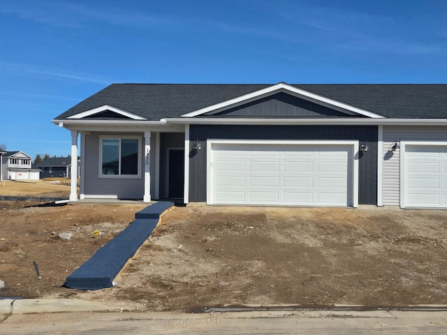 view of front of property featuring an attached garage, a shingled roof, and driveway