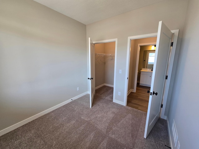 unfurnished bedroom with carpet, visible vents, baseboards, a spacious closet, and a closet