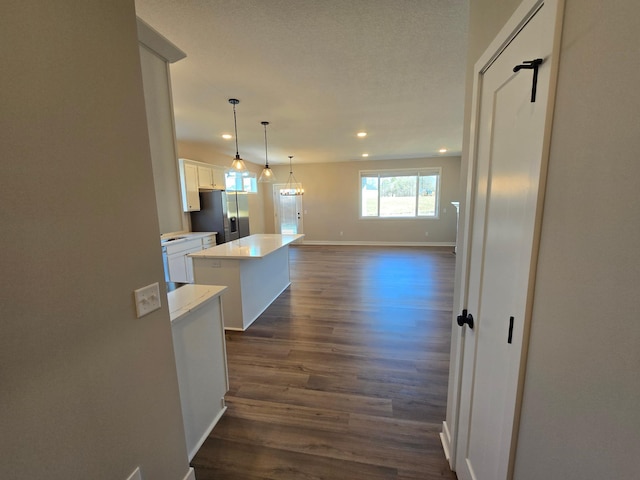 kitchen with a center island, dark wood-type flooring, stainless steel fridge with ice dispenser, light countertops, and white cabinetry