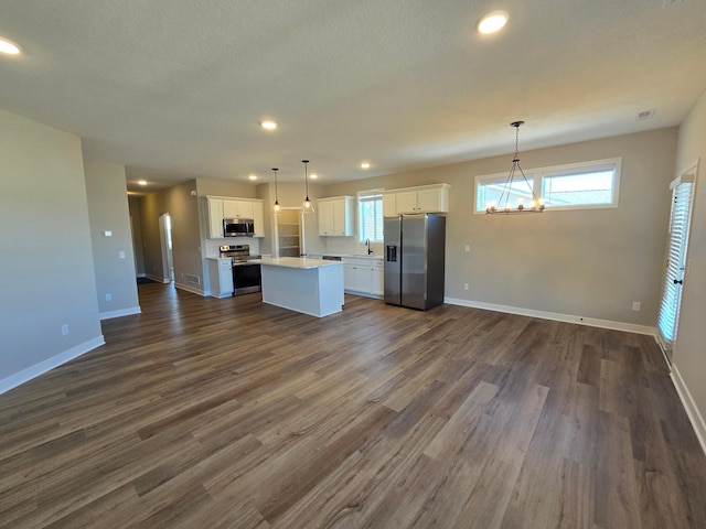 kitchen featuring a sink, appliances with stainless steel finishes, white cabinetry, open floor plan, and a center island