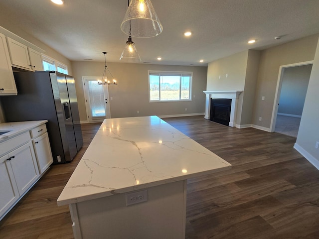 kitchen featuring a center island, open floor plan, recessed lighting, a fireplace, and white cabinets