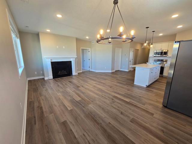 kitchen with open floor plan, light countertops, a fireplace, stainless steel appliances, and white cabinetry