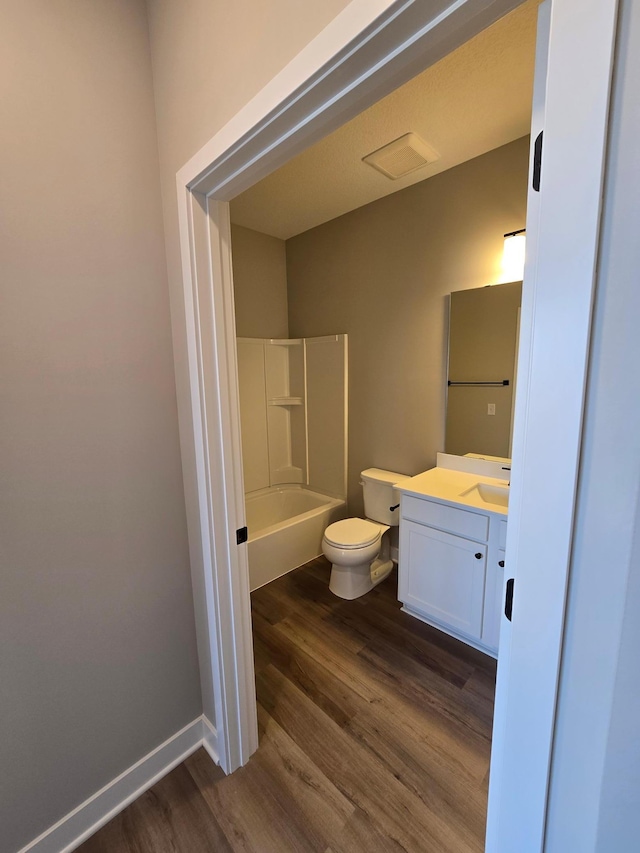 full bathroom featuring toilet, shower / washtub combination, wood finished floors, baseboards, and vanity