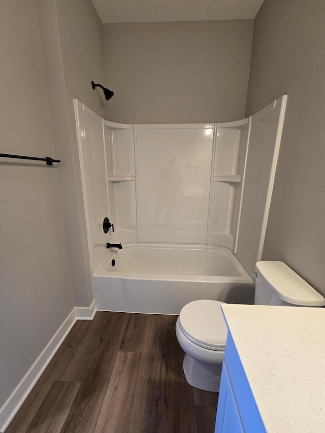 bathroom with vanity, wood finished floors, baseboards, shower / washtub combination, and toilet