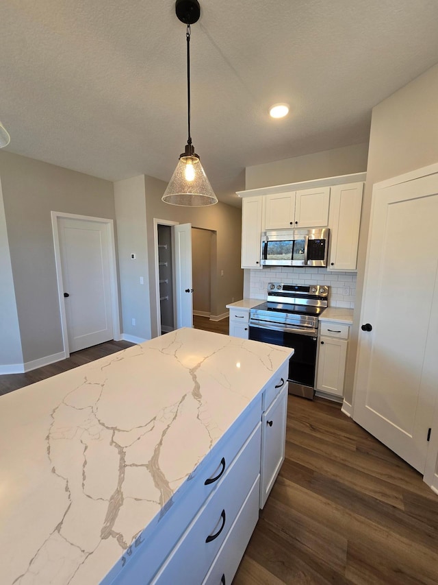 kitchen featuring dark wood-style floors, appliances with stainless steel finishes, white cabinetry, decorative light fixtures, and backsplash