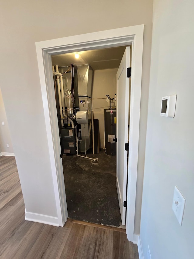 hall with wood finished floors, water heater, and baseboards