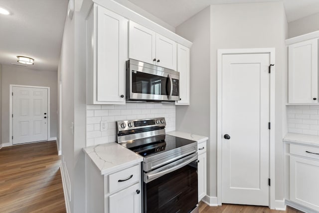 1330 Rose St, New Richmond, WI 54017 - kitchen with stainless steel appliances, tasteful backsplash, wood finished floors, and white cabinets
