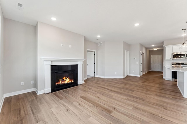 1330 Rose St, New Richmond, WI 54017 - unfurnished living room with a glass covered fireplace, baseboards, light wood-style flooring, and recessed lighting