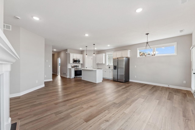 1330 Rose St, New Richmond, WI 54017 - unfurnished living room with a chandelier, baseboards, light wood-style flooring, recessed lighting, and a sink