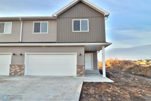 view of property featuring an attached garage, brick siding, and driveway