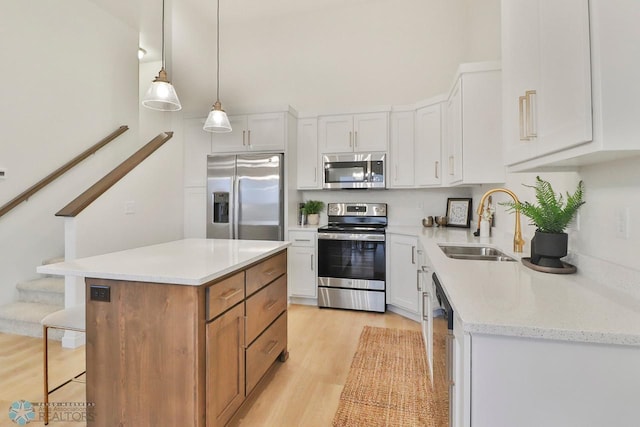 kitchen with a breakfast bar area, light wood-style flooring, a sink, appliances with stainless steel finishes, and white cabinetry