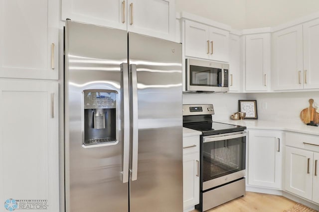 kitchen featuring white cabinets, appliances with stainless steel finishes, and light countertops