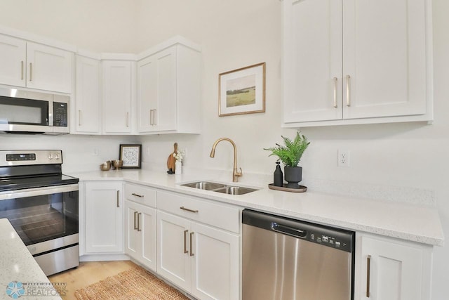 kitchen with light wood finished floors, white cabinetry, stainless steel appliances, and a sink