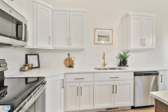 kitchen with visible vents, white cabinets, stainless steel appliances, and a sink