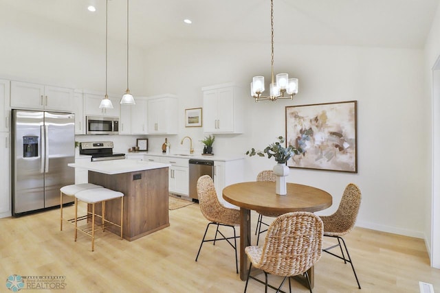 kitchen with stainless steel appliances, light countertops, light wood-style floors, white cabinetry, and a center island