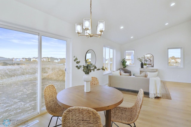 dining space with recessed lighting, a notable chandelier, lofted ceiling, and light wood-style floors