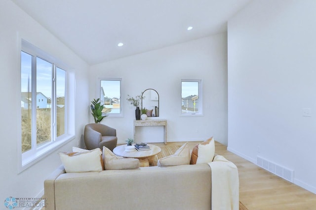 living room with visible vents, baseboards, lofted ceiling, light wood-style flooring, and recessed lighting