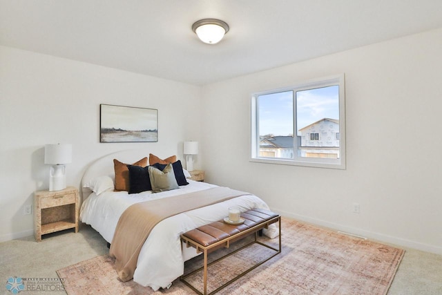 bedroom with light colored carpet and baseboards