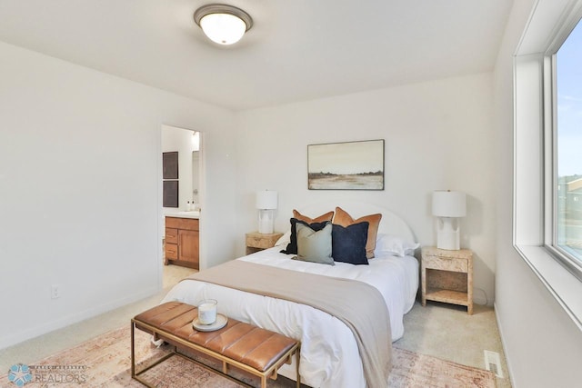 bedroom with baseboards, multiple windows, light colored carpet, and connected bathroom