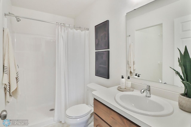 bathroom with a shower stall, toilet, and vanity