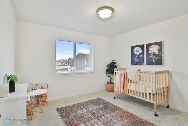 carpeted bedroom with a crib and baseboards