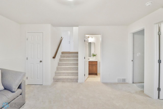 living room with visible vents, light colored carpet, and stairs