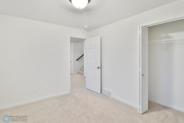 unfurnished bedroom featuring visible vents, a closet, carpet floors, and baseboards