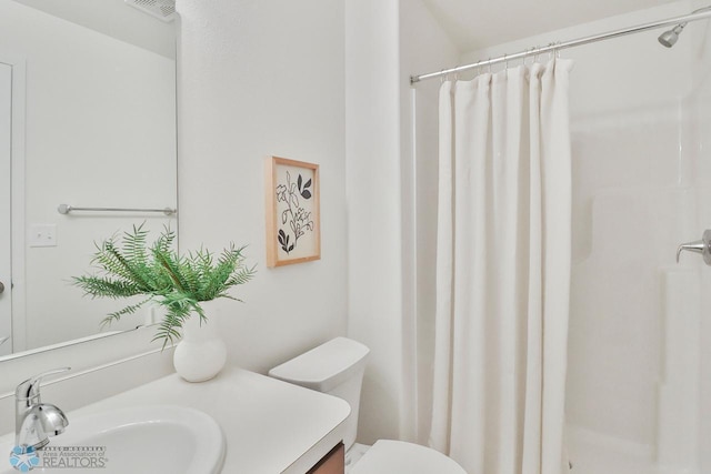 bathroom with vanity, a shower stall, and toilet