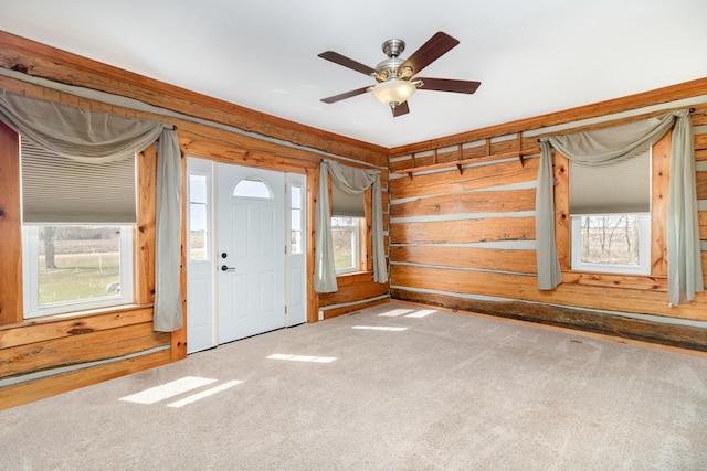 entrance foyer with plenty of natural light, wooden walls, and carpet flooring