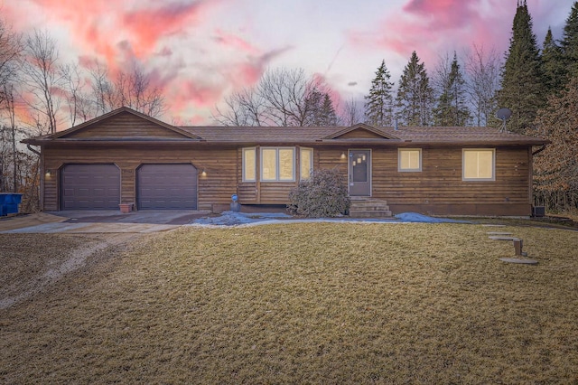 single story home with a front lawn, an attached garage, and driveway